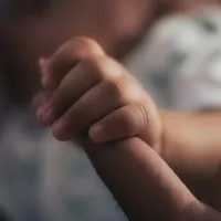 Mão do bebê segurando o dedo de um adulto